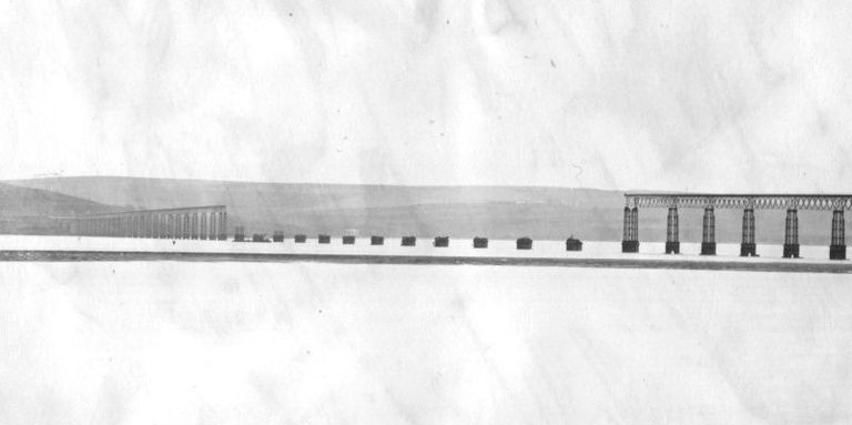 Historische Schwarzweiß-Aufnahme der Brücke. Der Mittelteil ist vollständig eingestürzt; nur die steinernen Fundamente der Brückenpfeiler ragen noch aus dem Wasser.